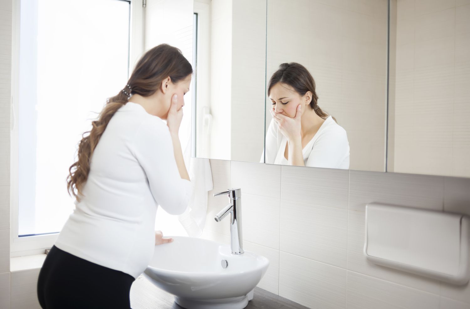 Pregnant woman with her hand over her mouth fighting nausea