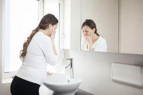 Pregnant woman with her hand over her mouth fighting nausea