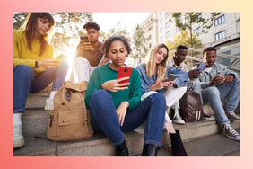 Teens sitting on steps outside looking at phones.