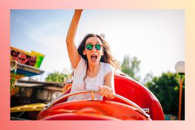 Woman riding a roller coaster with her arm up in the air.