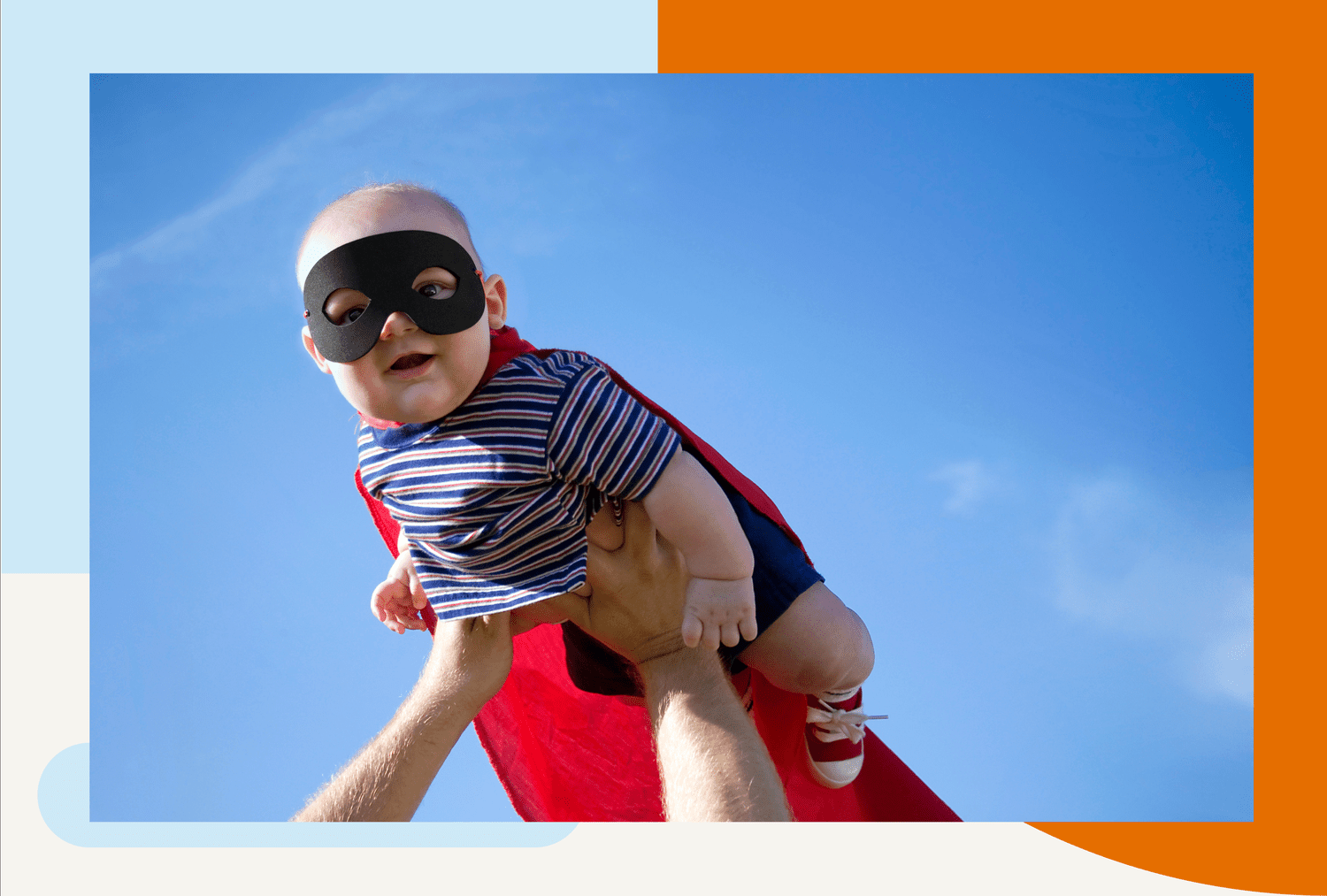 baby wearing a superhero costume being lifted in the air