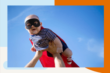 baby wearing a superhero costume being lifted in the air