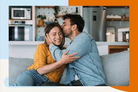 a couple sitting on their living room couch and kissing 