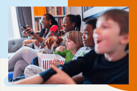 a family sitting on the couch with their dog watching a movie and eating popcorn